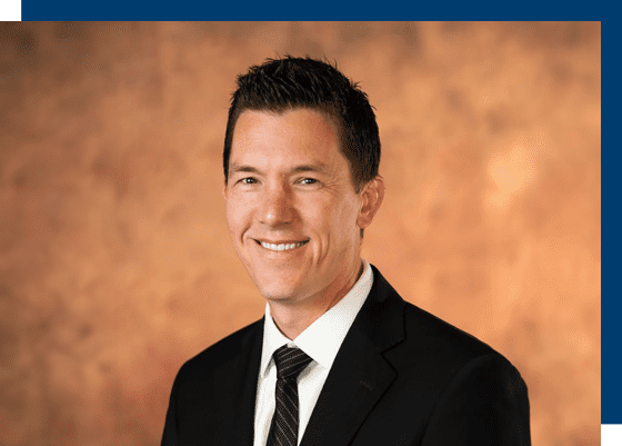 A man in suit and tie smiling for the camera.