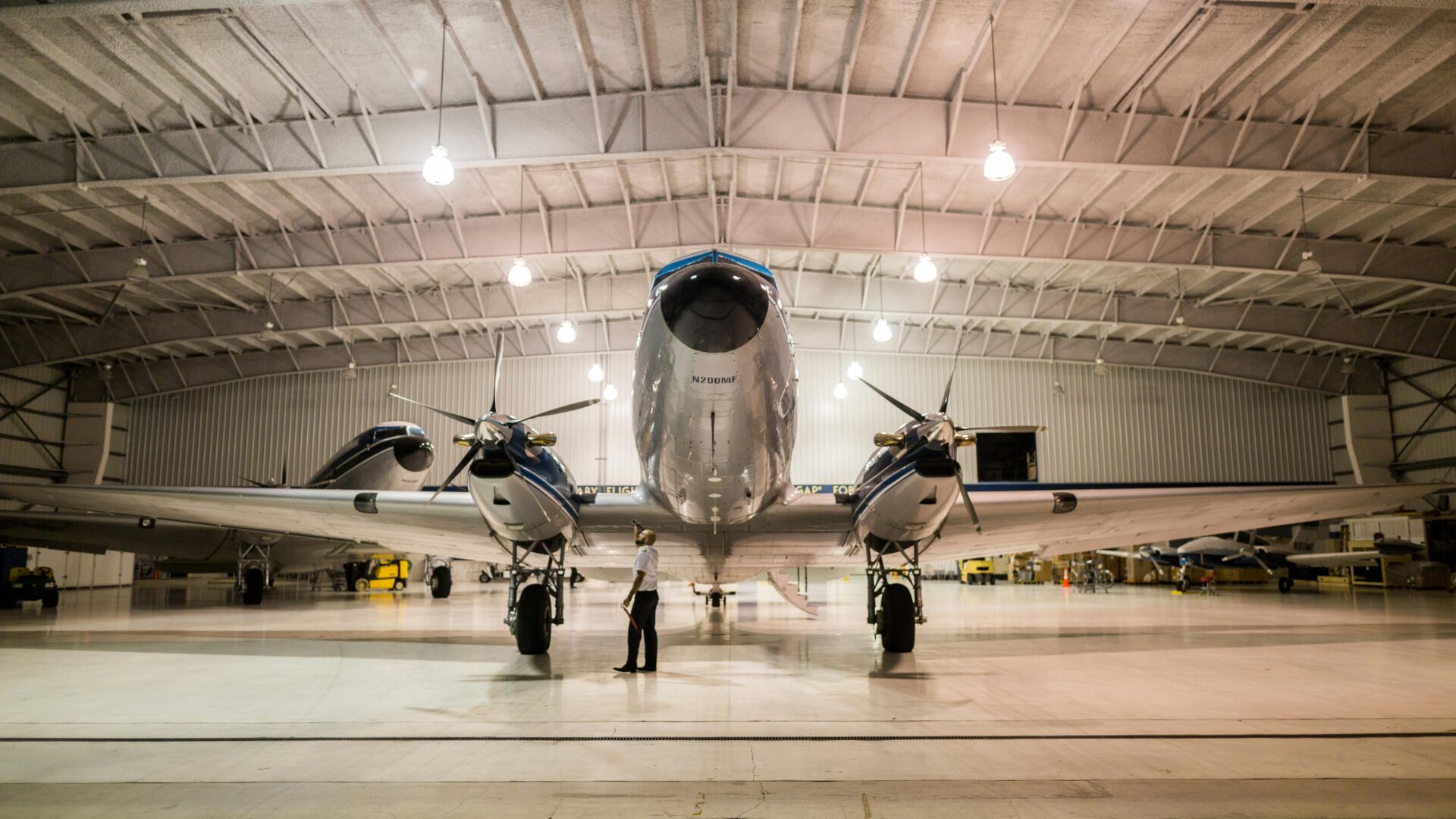 A large airplane in an airport hangar with two men standing next to it.