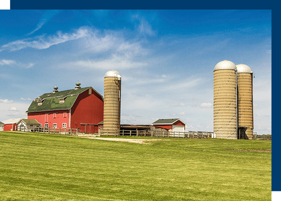 A red barn with two silos in the background.