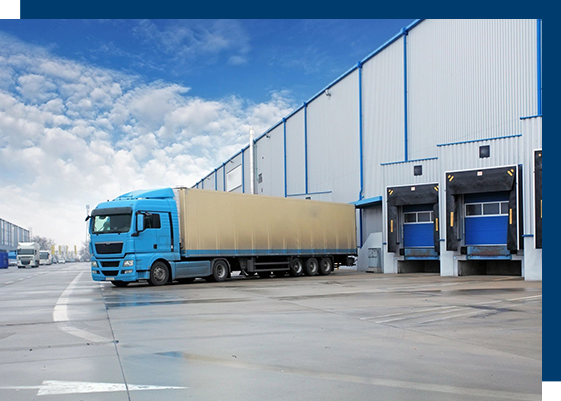 A blue truck parked in front of a warehouse.