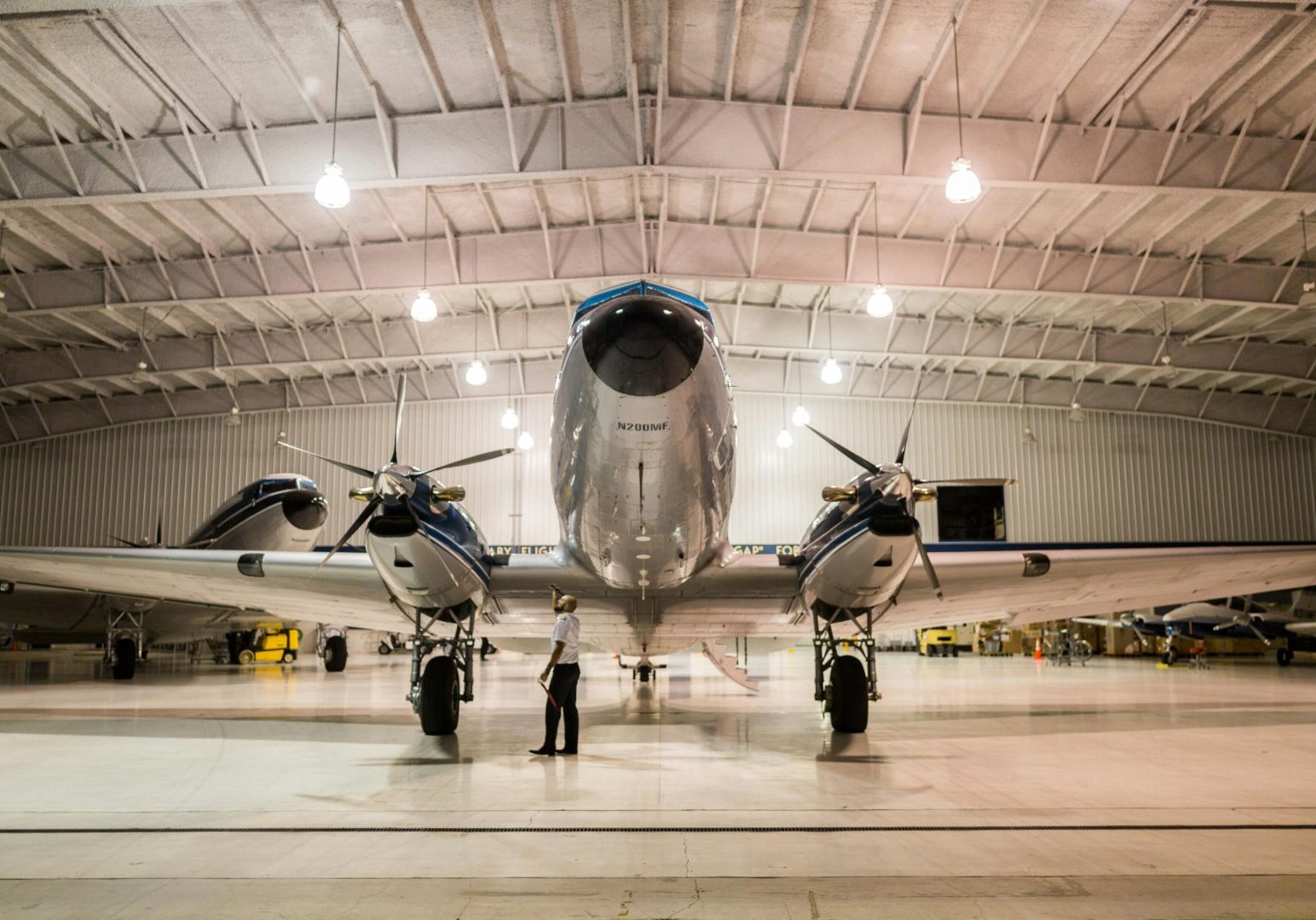 A large airplane in an airport hangar with two men standing next to it.